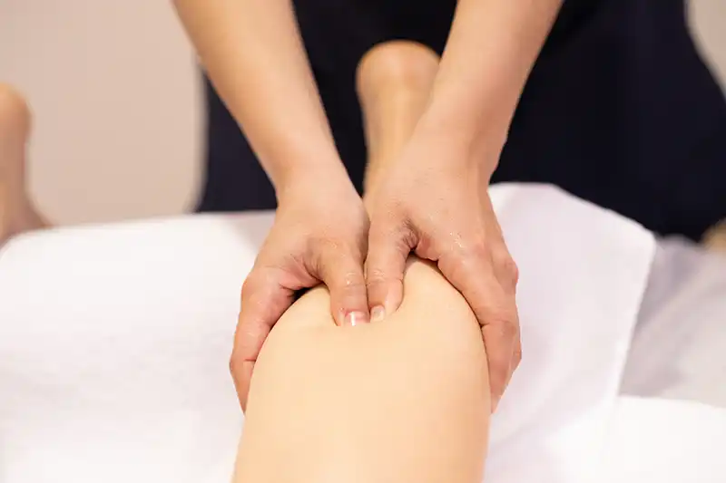 Massage therapist is holding calf of patient, providing massage service